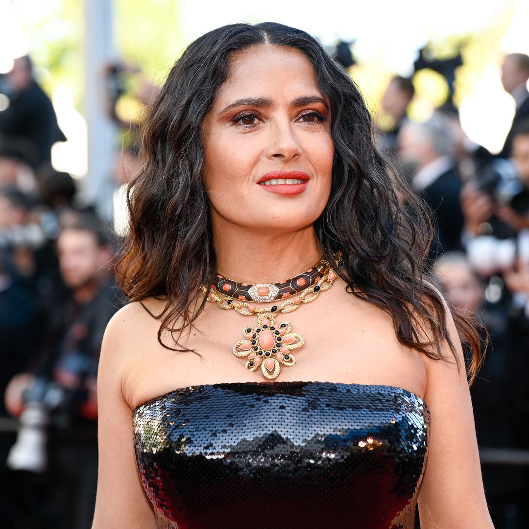 Salma Hayek smiling at a red carpet event, showcasing her signature elegance